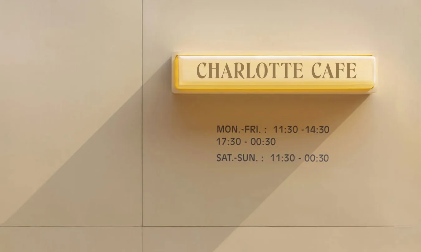 Yellow Charlotte Cafe sign with opening hours on a beige wall