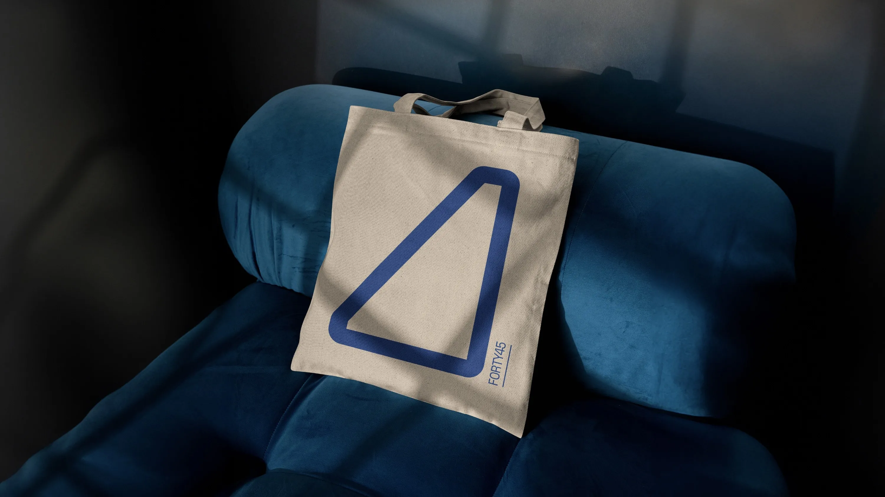 Forty 45 cream tote bag with blue outlined logo mark on a velvet chair
