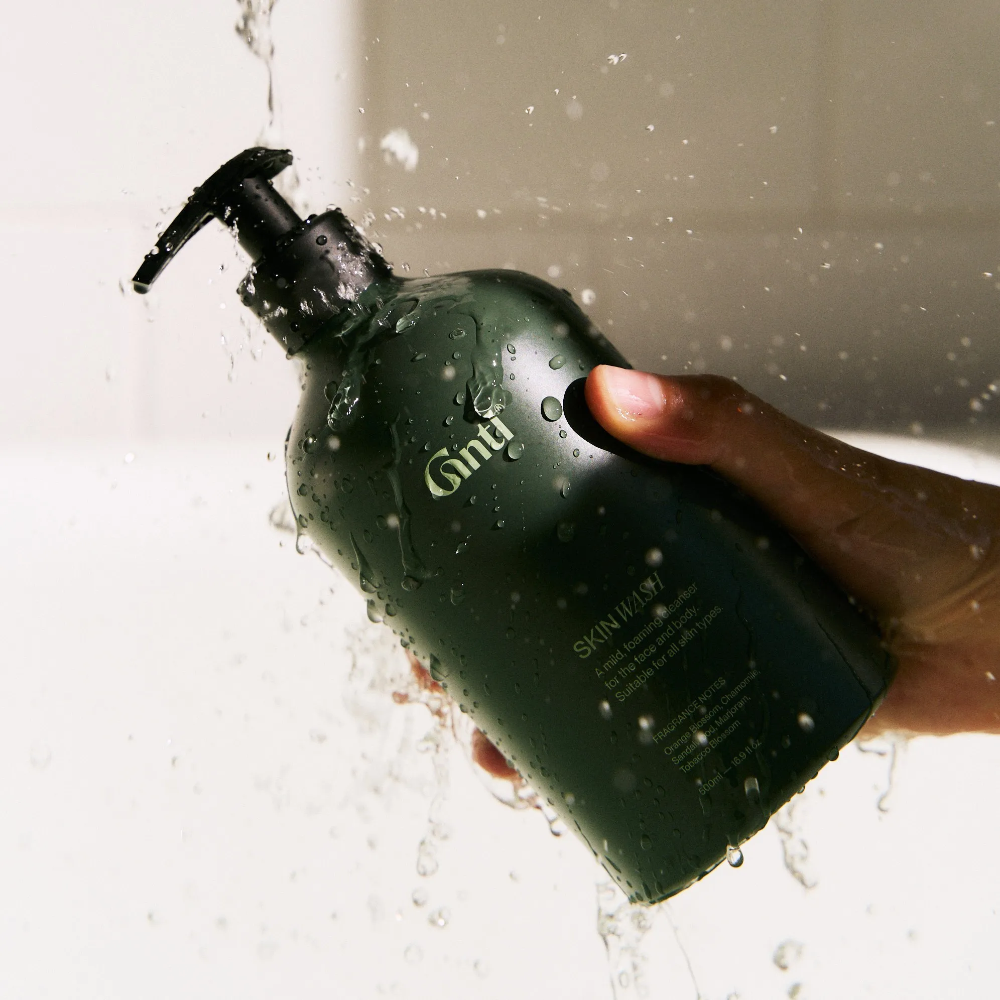 Wet green Gntl pump bottle held under running water