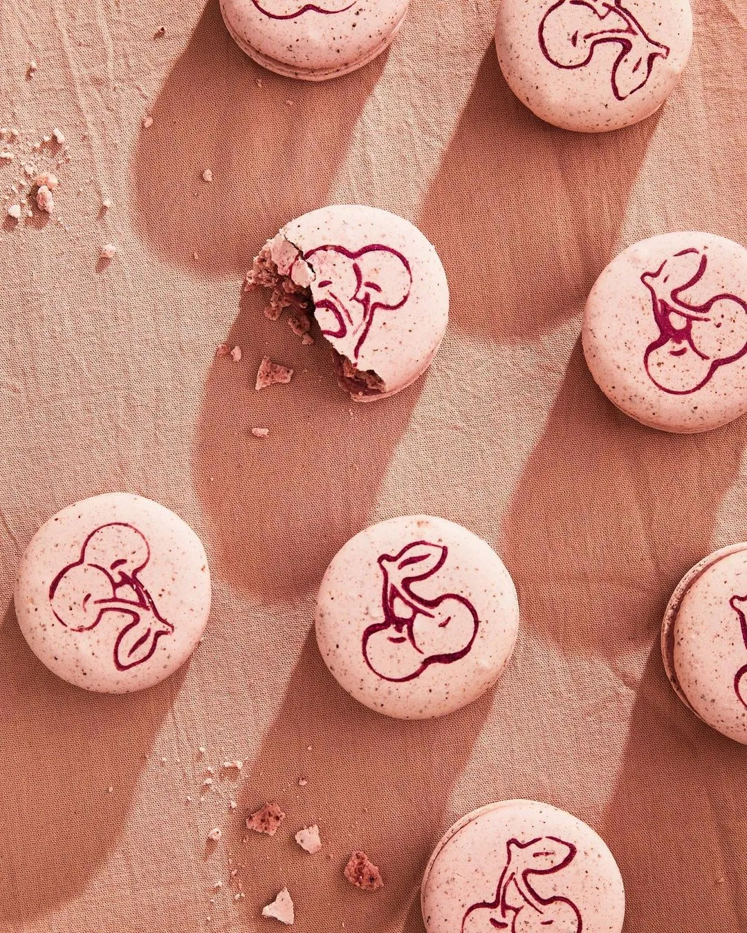 Pink macarons stamped with a burgundy cherry illustration