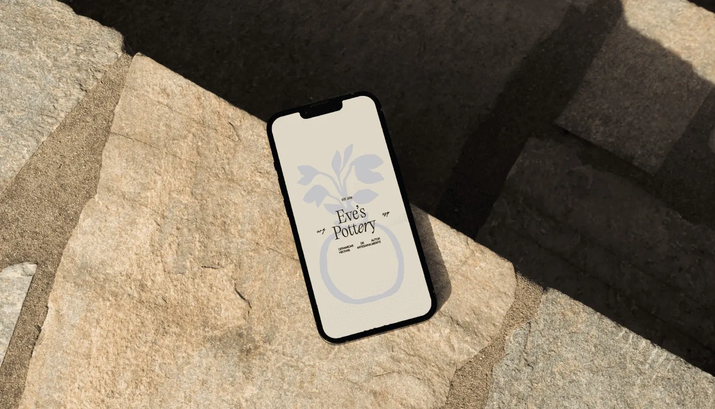 Eve's Pottery vase illustration on a phone screen over stone steps