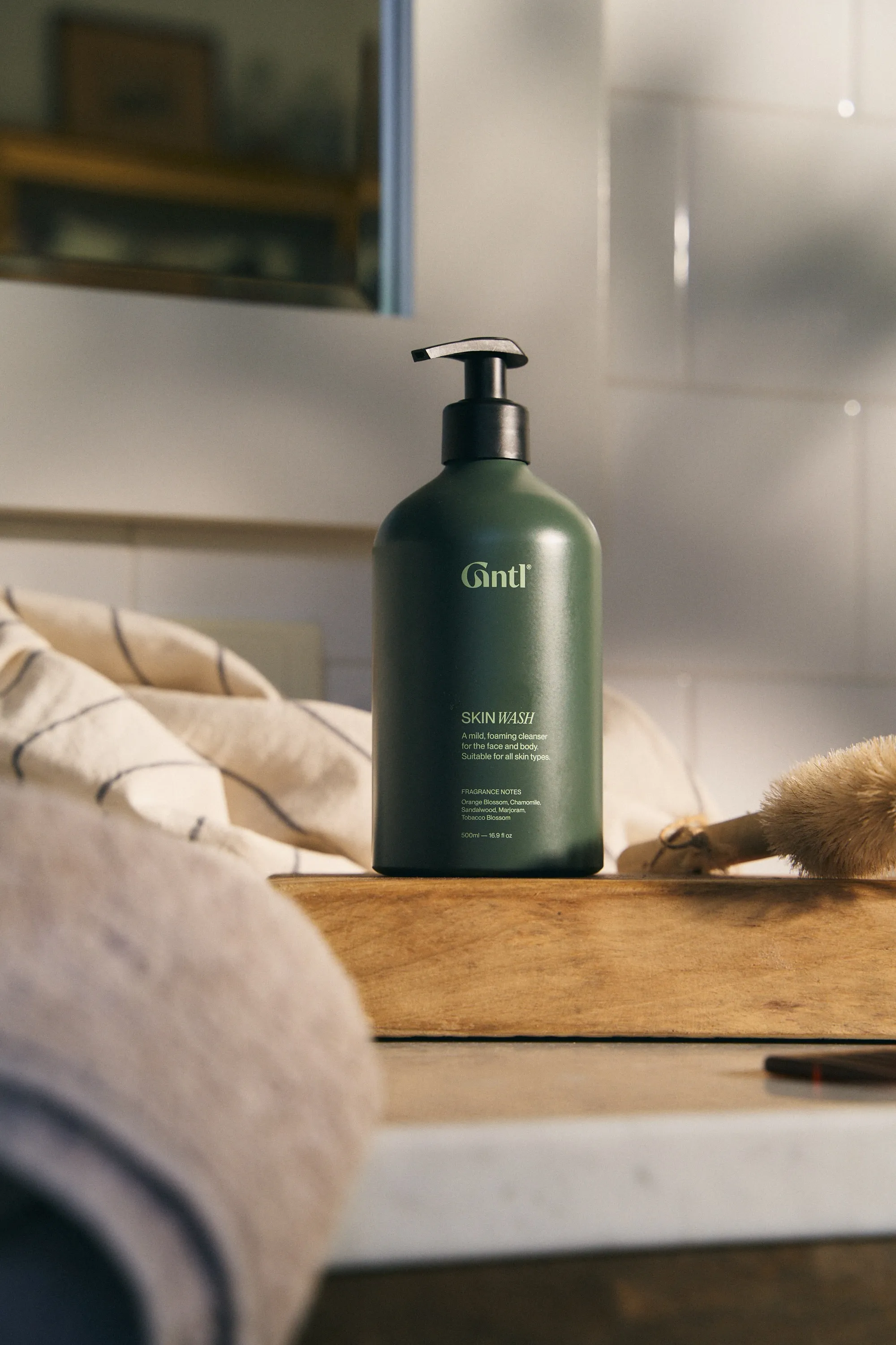 Gntl Skin Reset pump bottle on a wooden board beside towels and a brush