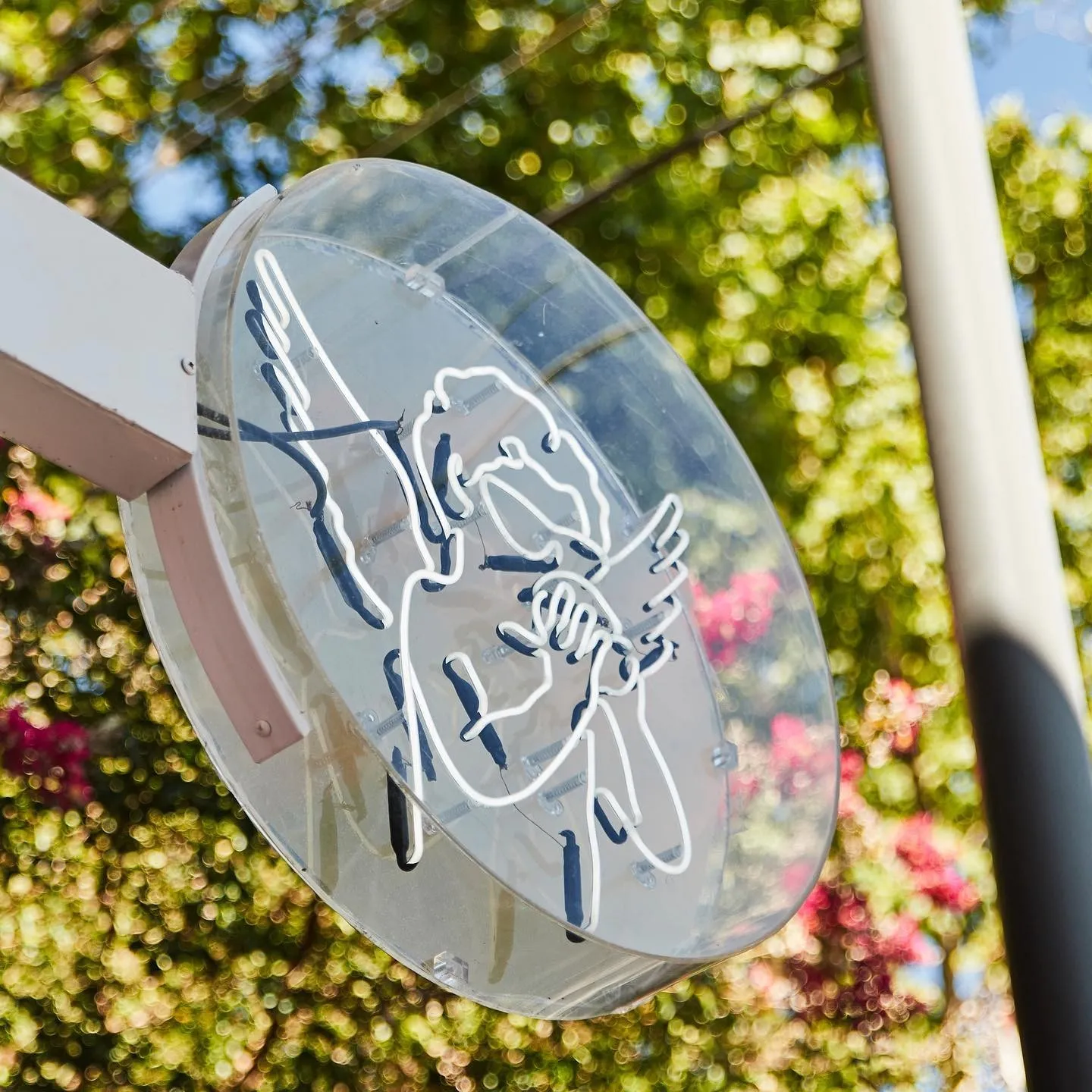 Round Café Jazmín neon sign showing an angel against trees