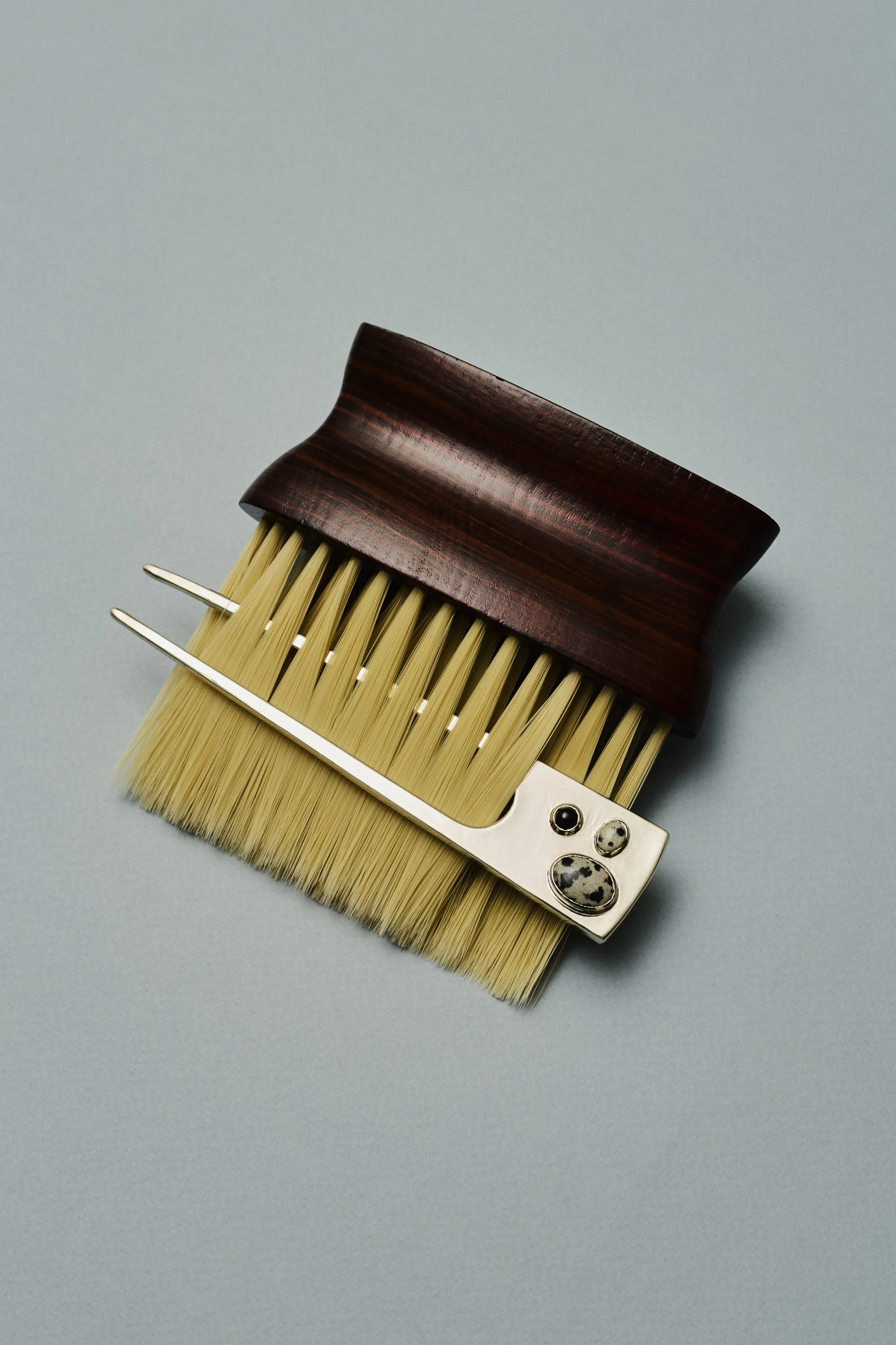 Wooden brush with a silver hair pin set with spotted stones, on pale blue