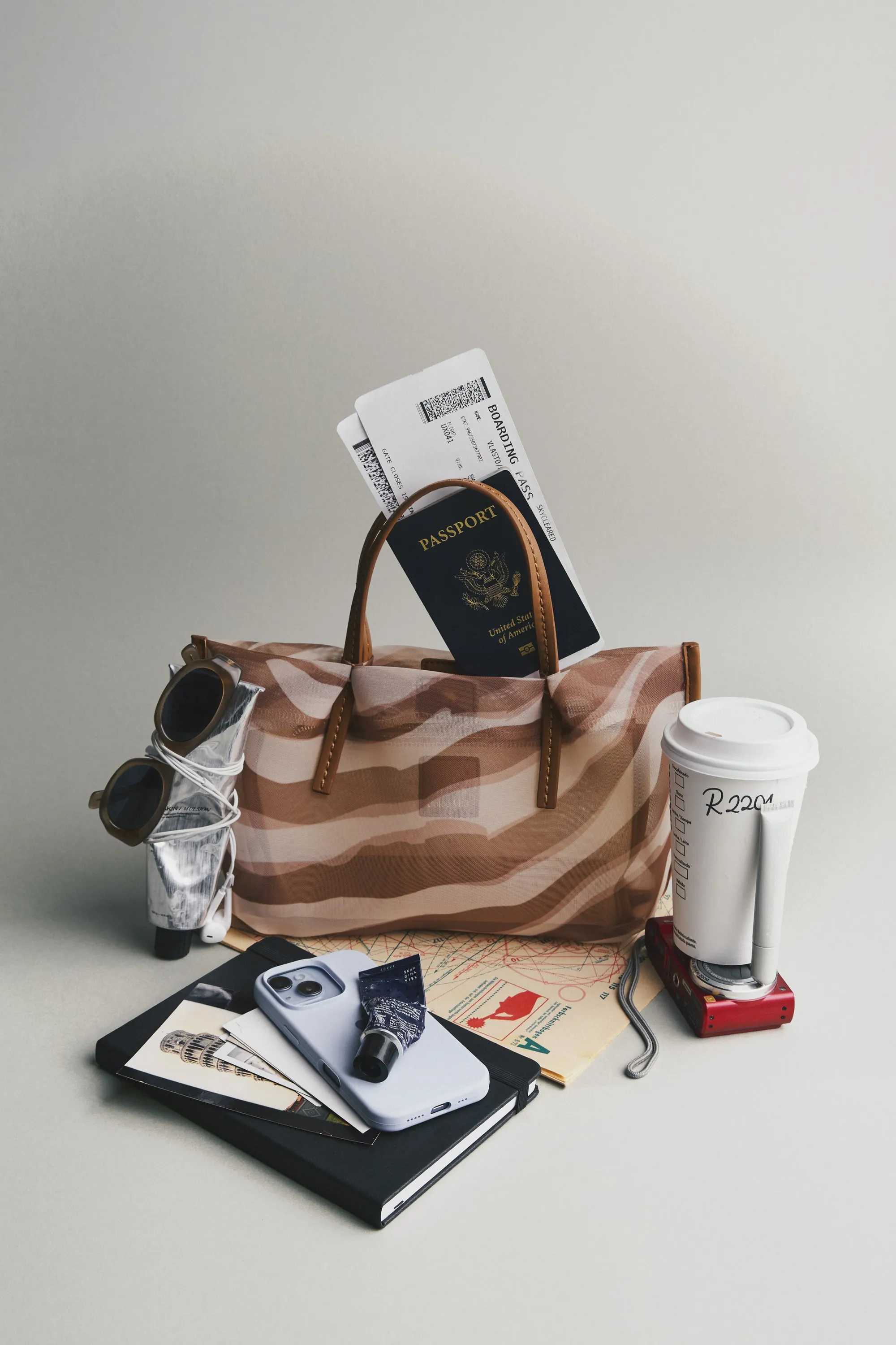 Striped tote with a passport, boarding pass, sunglasses, coffee cup and phone