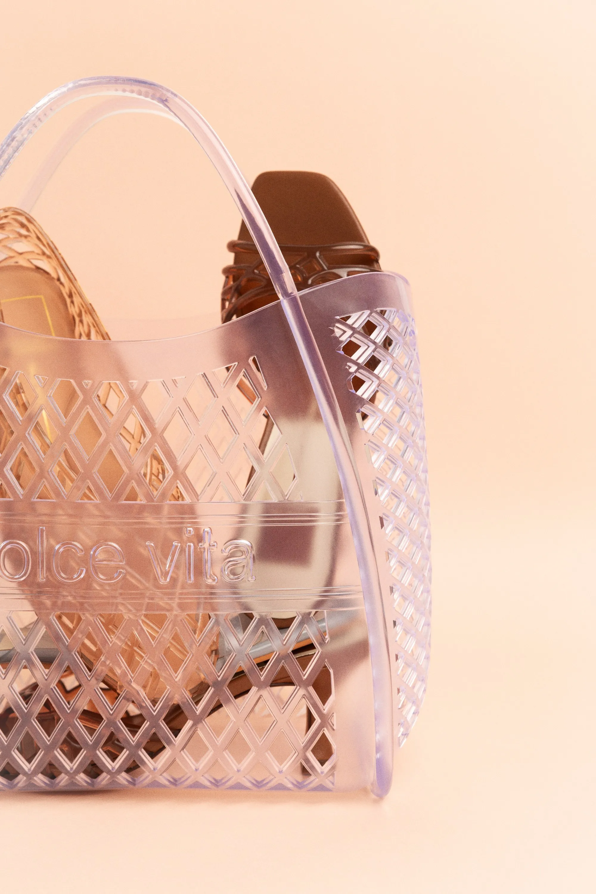 Clear lattice Dolce Vita tote holding sandals, on peach