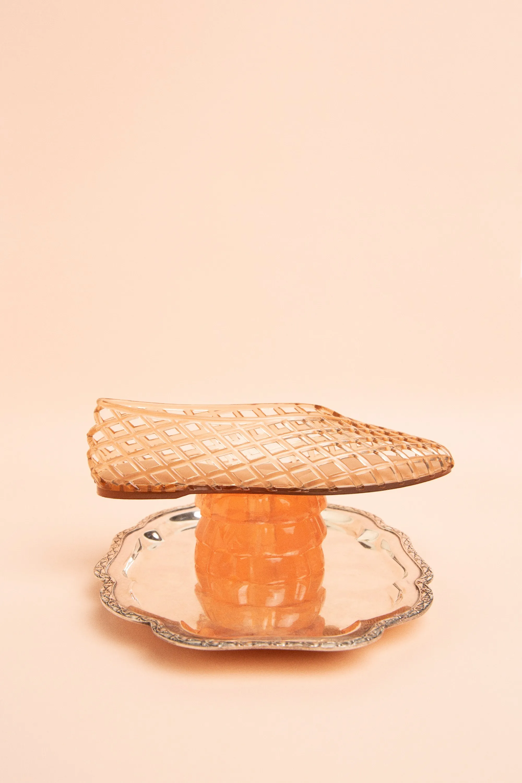 Woven Dolce Vita jelly flat resting on a peach jelly mold on a silver dish, on peach