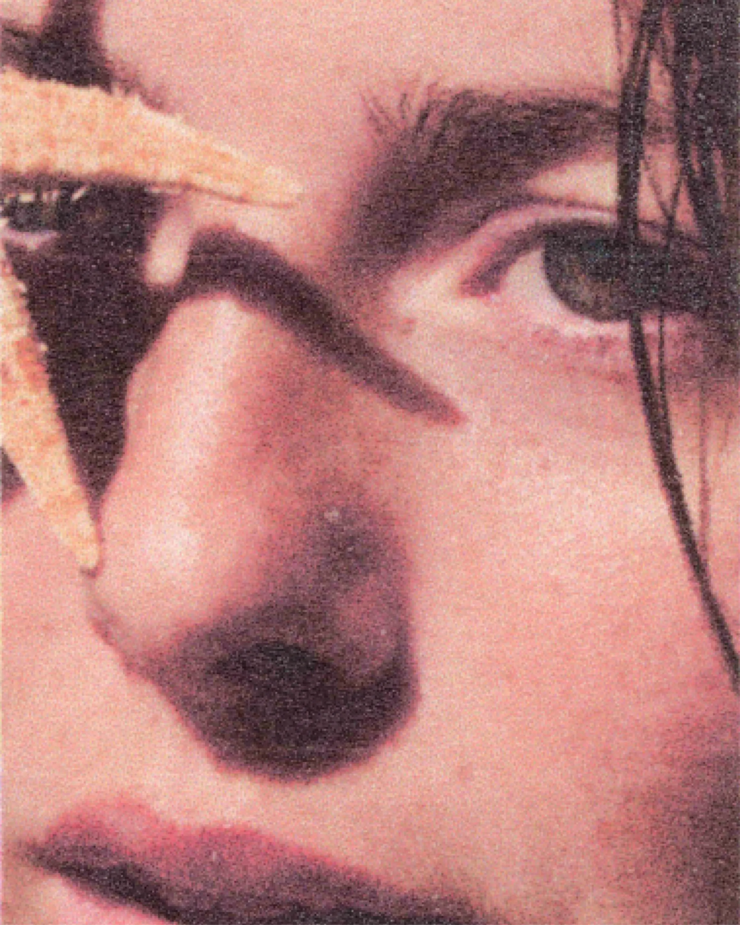 Close-up of a wet face with a strand of raffia laid across it