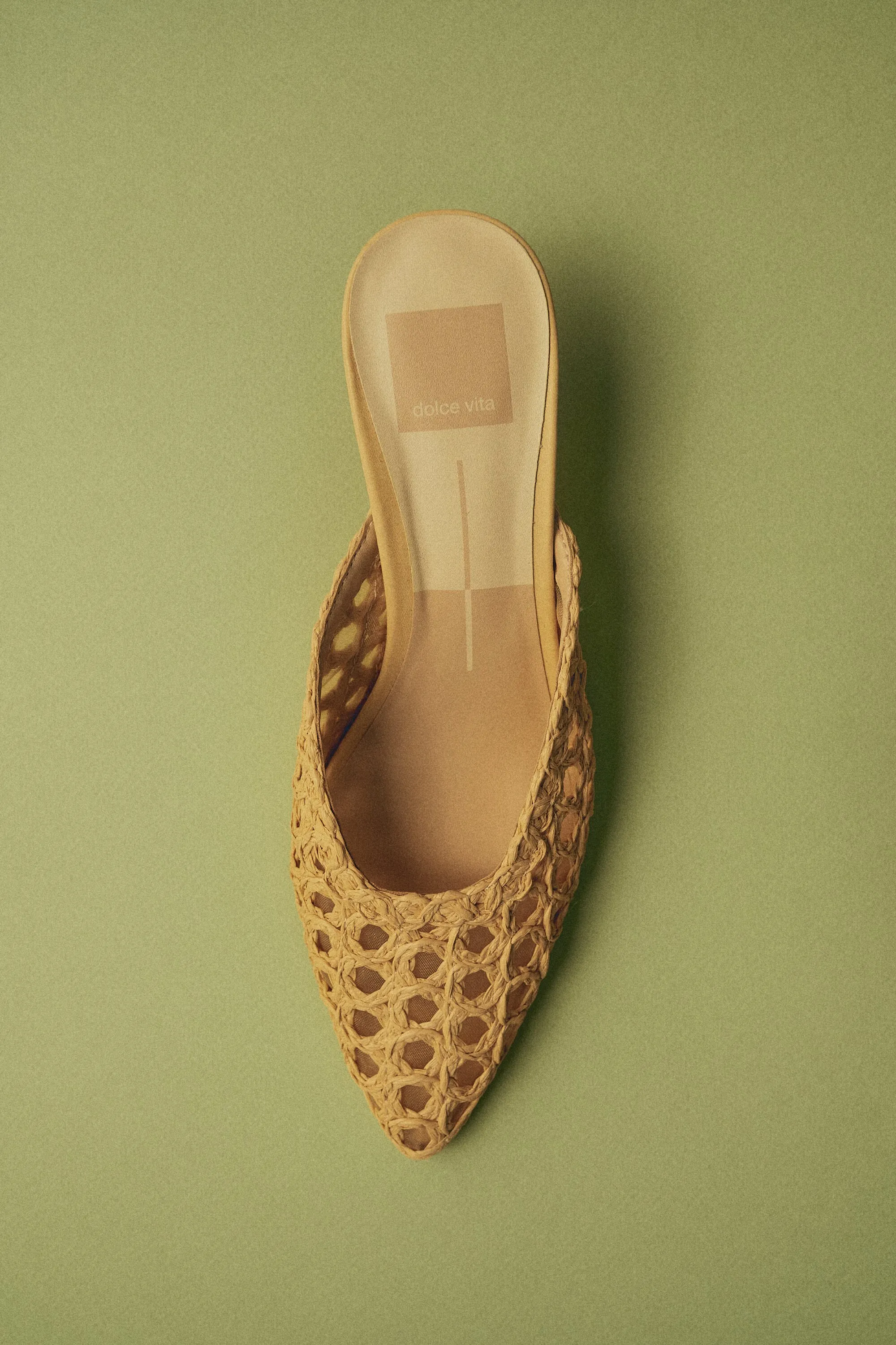 Woven raffia mule on an olive green background