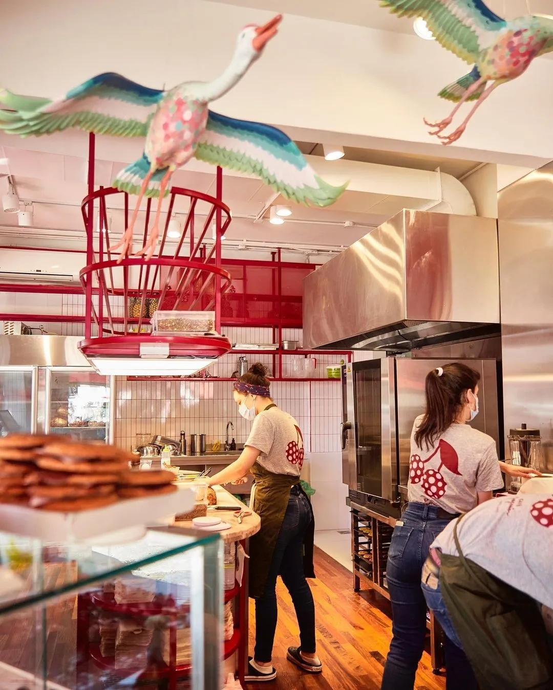 Café Jazmín kitchen with staff in cherry print shirts and hanging bird sculptures