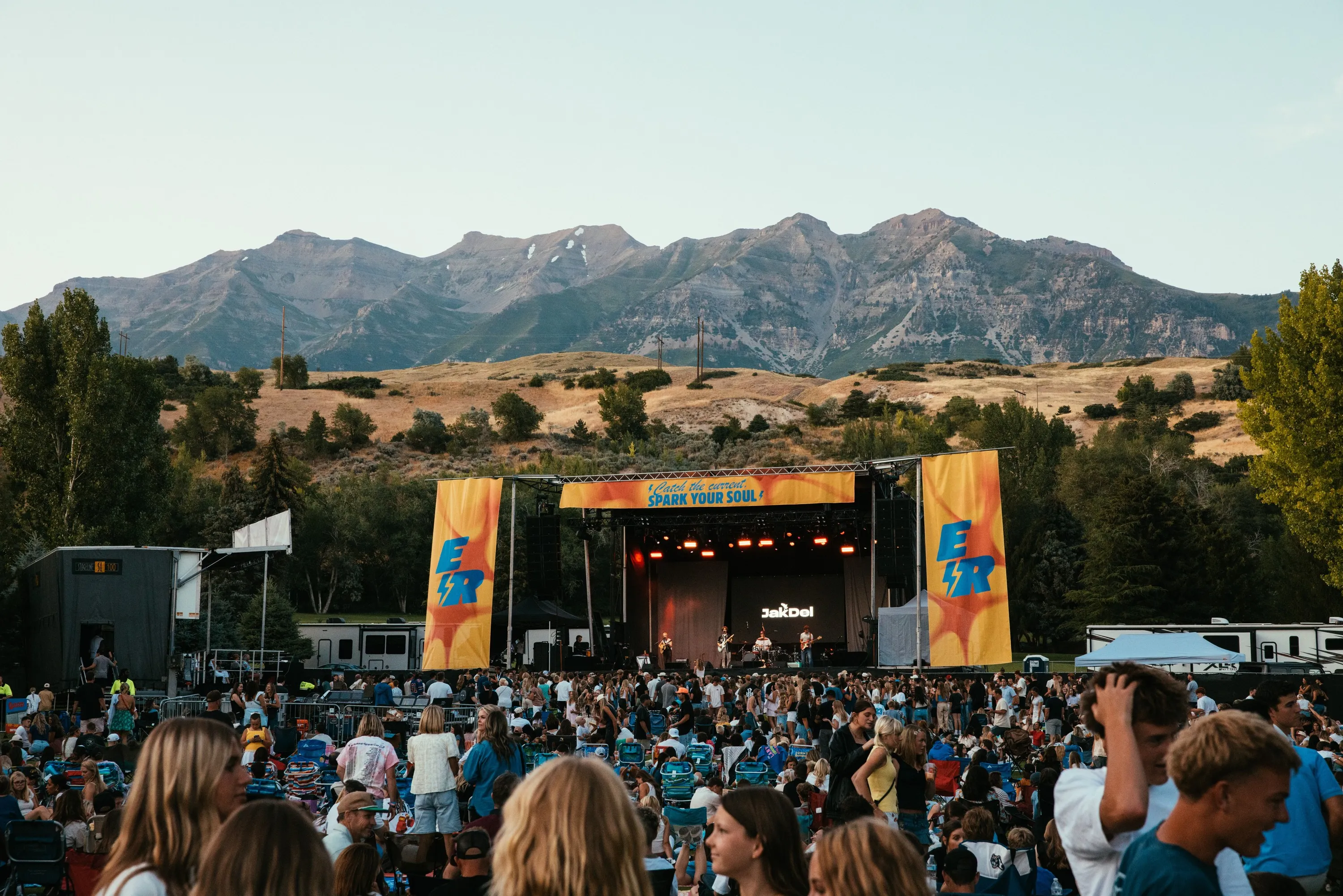 Electric Revival outdoor stage with orange banners, crowd and mountains behind