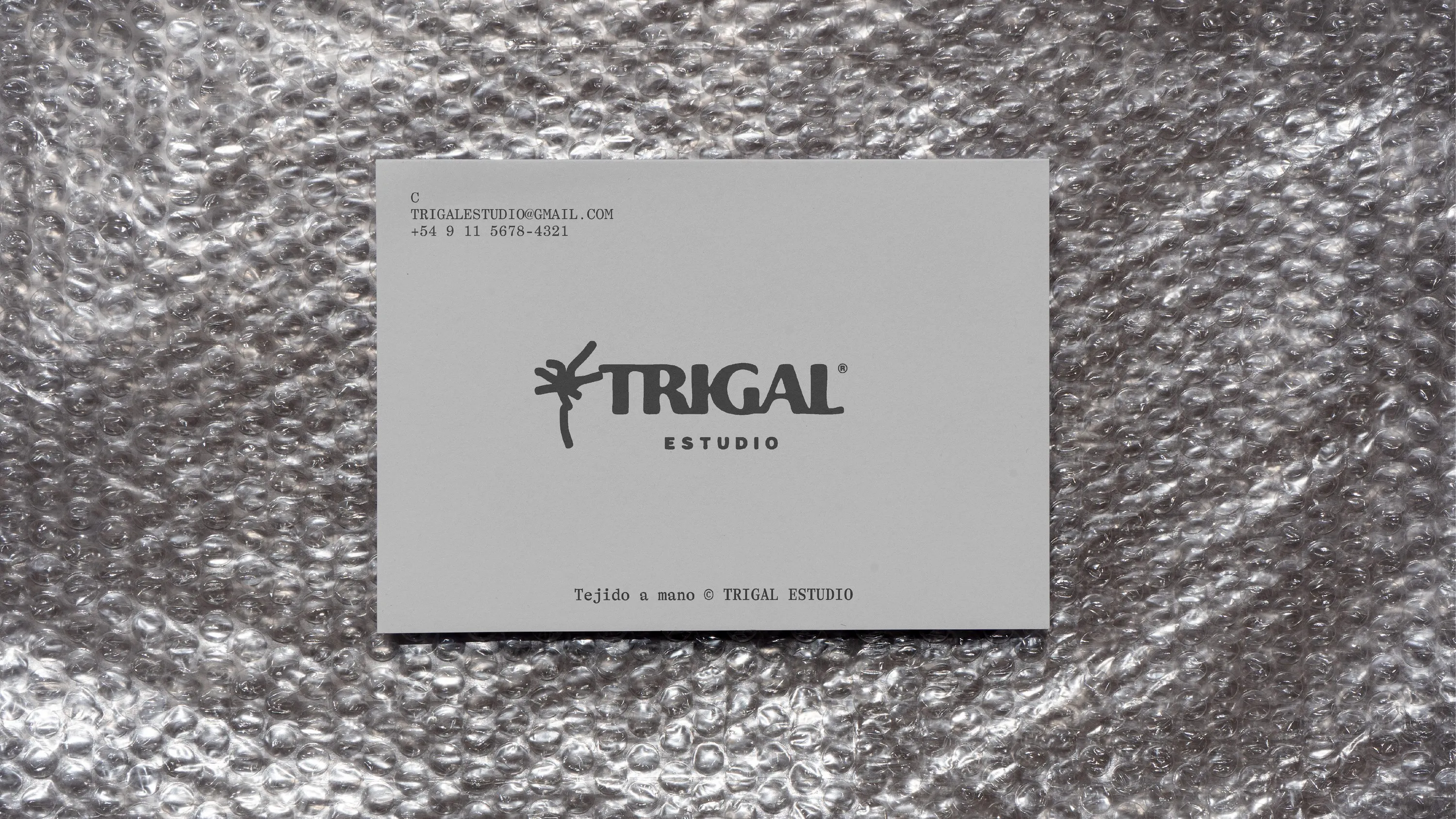 Grey Trigal Estudio business card on bubble wrap, Tejido a mano